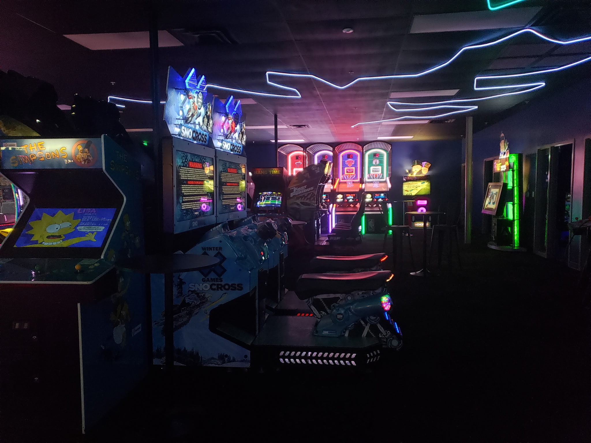 Neon-lit arcade cabinets under ribbon lighting at Play Money Fort Pierce